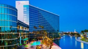 aerial of exterior of Hyatt Regency Long Beach with view of large pool in California, USA during day with blue sky